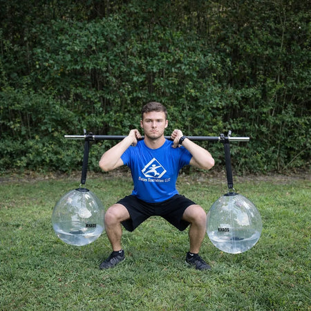 Athlete performing a front rack squat with the KHAOS® Yoke, utilizing suspended water balls to drive anterior-load stabilization and maximize force transmission through the throwing chain.