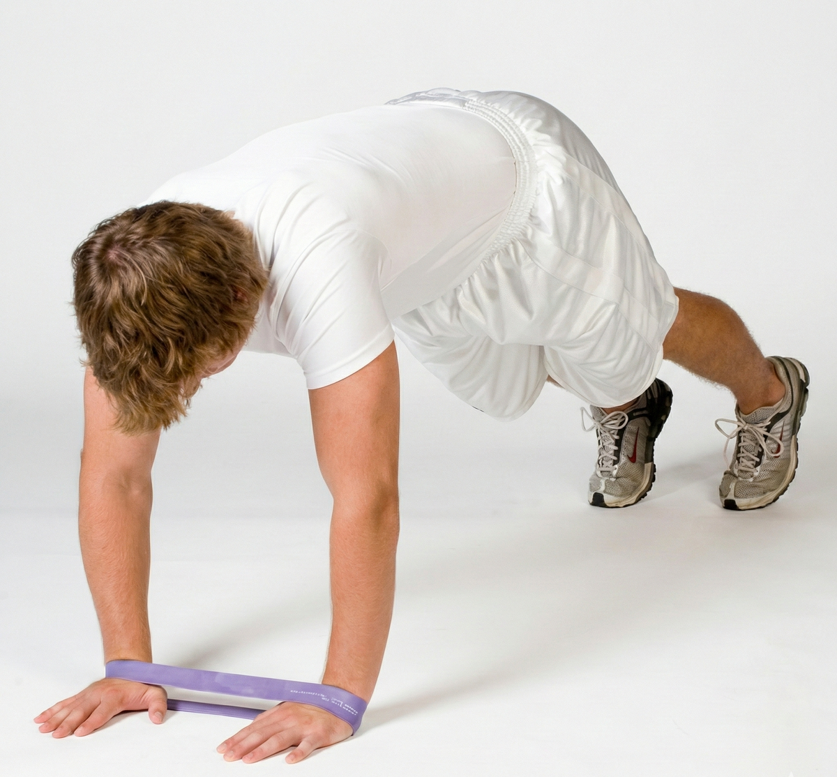 Athlete in a push-up stance utilizing a TAP® Exercise Band around the wrists to engage the serratus anterior and promote scapular stability during an upper-body activation sequence.