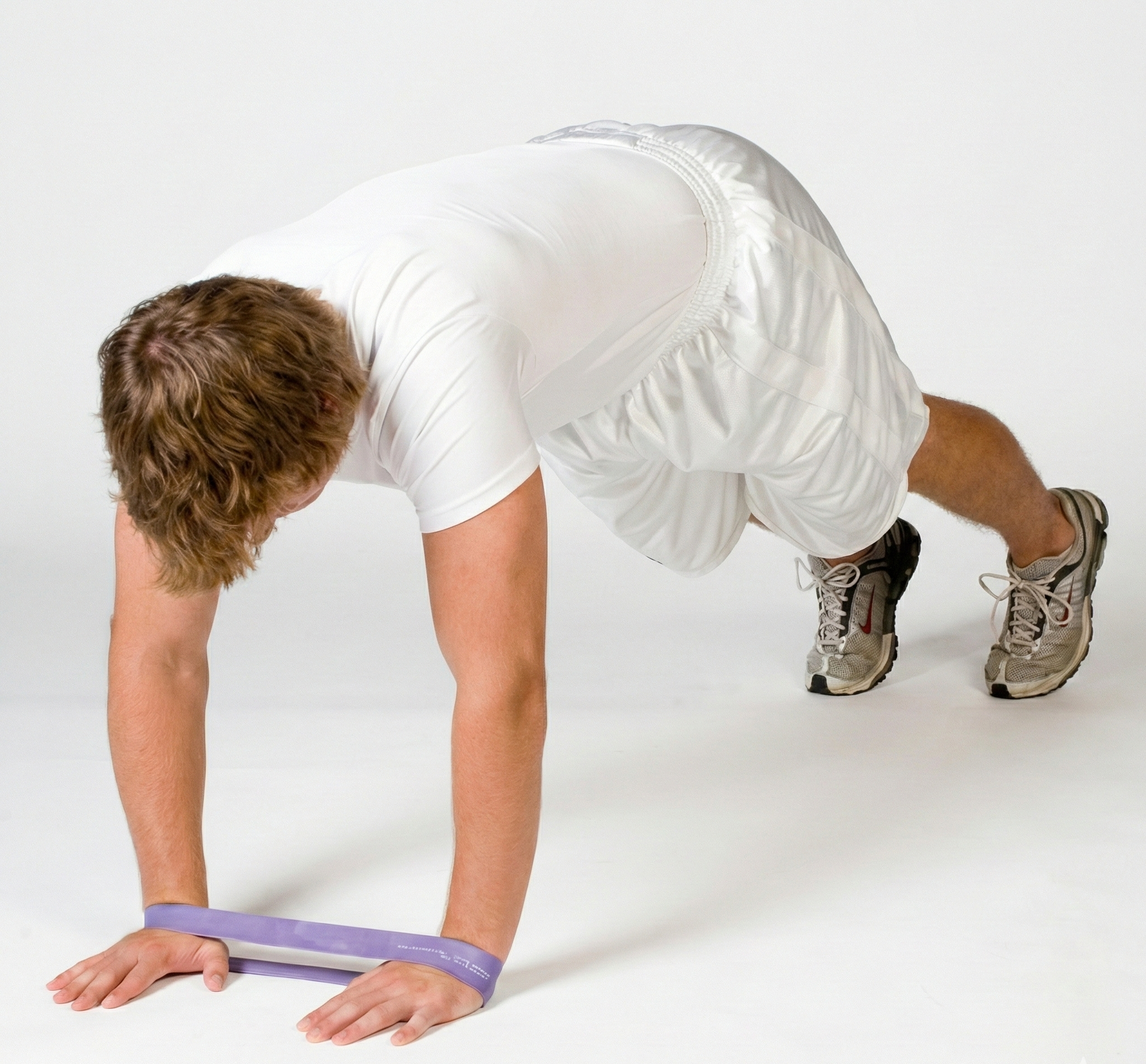 Athlete in a push-up stance utilizing a TAP® Exercise Band around the wrists to engage the serratus anterior and promote scapular stability during an upper-body activation sequence.