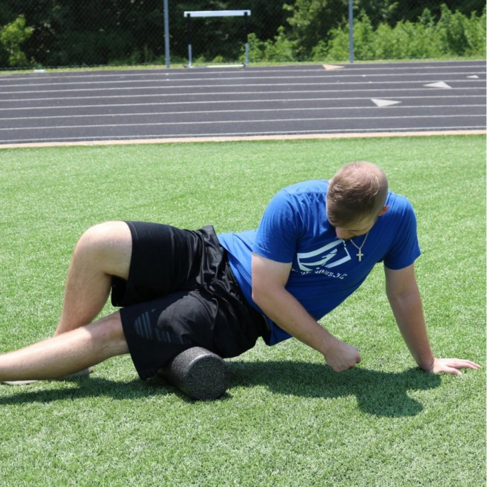 Athlete using a foam roller to target the outer quad and hamstring.