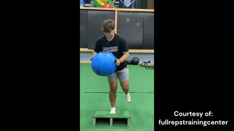 Athlete balancing on one leg while stabilizing core and pressing out the Blue Khaos® Water Ball. Single-leg balance and core strength training with unstable load.
