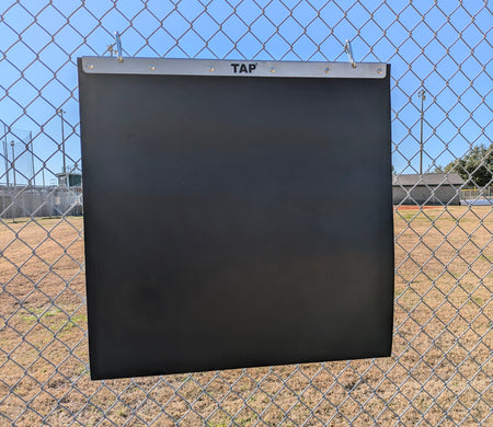 TAP® Portable Plyo Mat is hung from a chain link fence using the hooks provided with the product for which it is ready to have weighted balls or baseballs being thrown at it