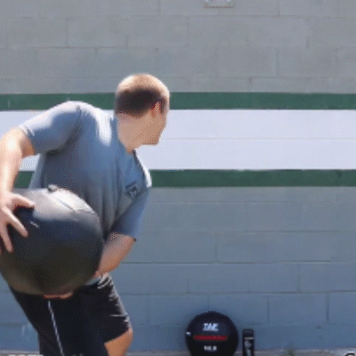 Athlete doing rotational side throws against a brick wall to strengthen core muscles.