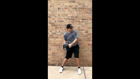 Athlete performing side-to-side cross-body handle medicine ball slams against a brick wall—targeting core strength and improving stability through dynamic rotational movement.