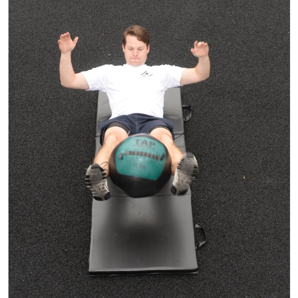 Soft Medicine Ball in between legs fully extended as a weighted reverse plank to strengthen core muscles