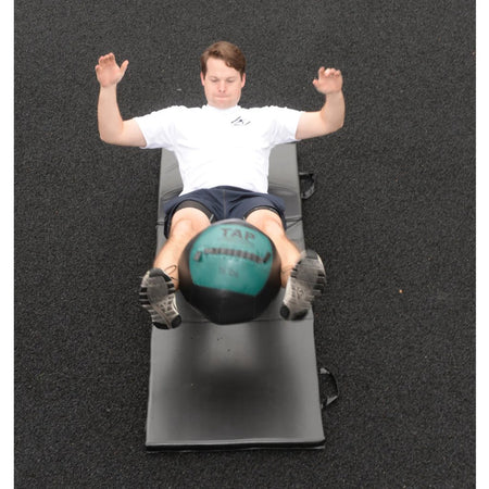 Soft Medicine Ball in between legs fully extended as a weighted reverse plank to strengthen core muscles