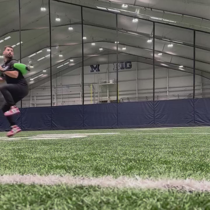 Video of an athlete executing a pitching delivery with a KHAOS Bulgarian Water Bag across the shoulders, utilizing rhythmic perturbations to stabilize the throwing chain and maximize rotational power.