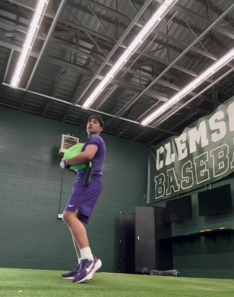 Athlete performing pitching-specific core training with the KHAOS Bulgarian Water Bag, utilizing shifting water resistance to drive neuromuscular control and power transmission through the throwing chain.