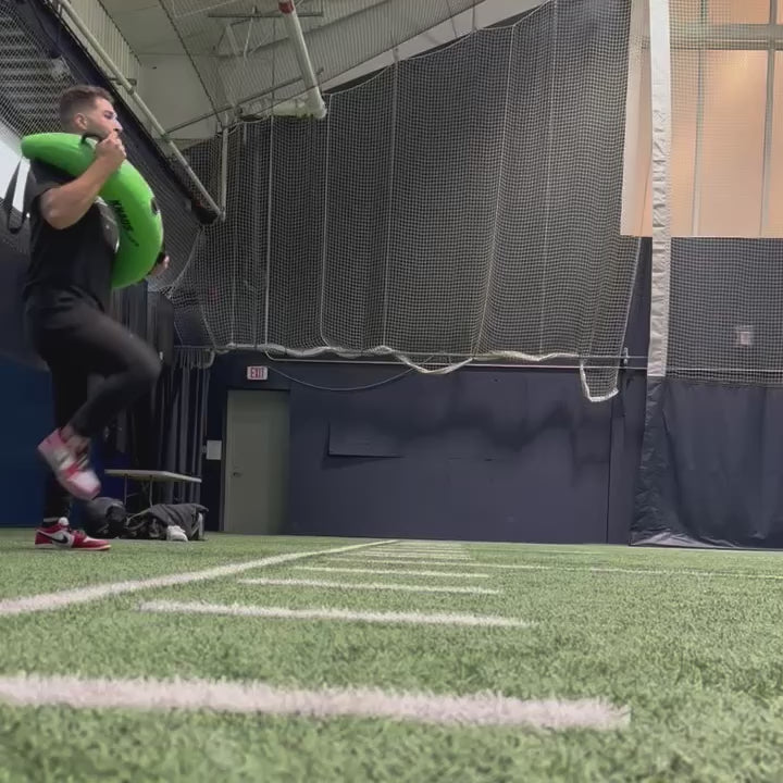 Athlete performing a pitching delivery with the KHAOS Bulgarian Water Bag, utilizing dynamic water perturbations to stabilize the throwing chain and maximize power transfer through the arm.