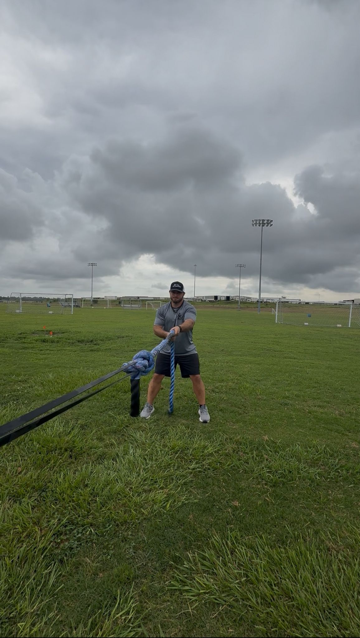 From a front perspective, an athlete is shown intently performing hand-over-hand rope pulls, engaging their upper body and core as they pull the rope towards them.

