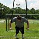 Athlete in a suspended push-up position with hands on the TAP® Suspension Trainer handles.