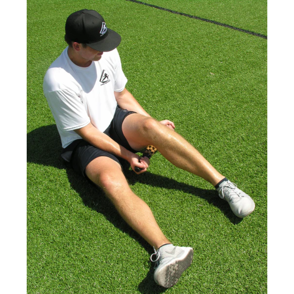 An athlete uses the relief stick for a myofascial release of the hamstring muscle. 