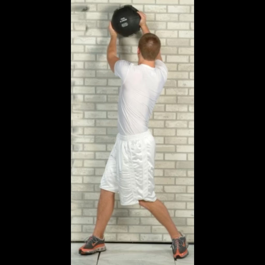 Athlete executing overhead side chops with a Double Handle Medicine Ball against a wall—developing rotational power, shoulder endurance, and core stability.