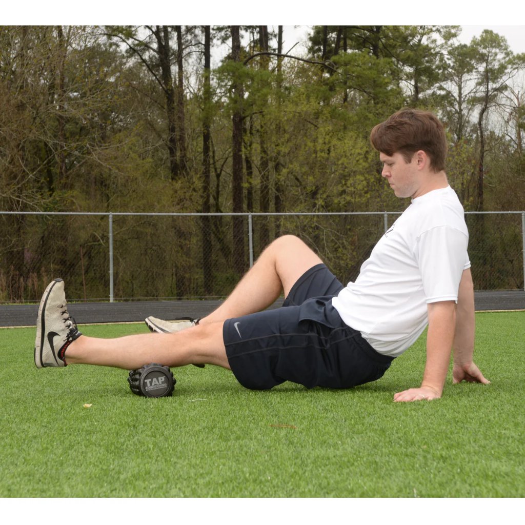 Athlete performing calf muscle recovery with massage roller to loosen tight tissue.