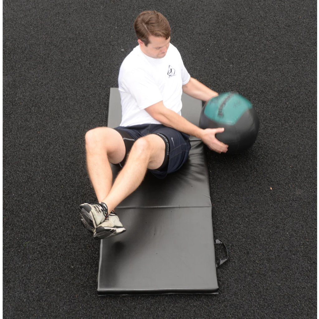 Athlete using 16lb soft medicine ball in Russian twist for core stability.