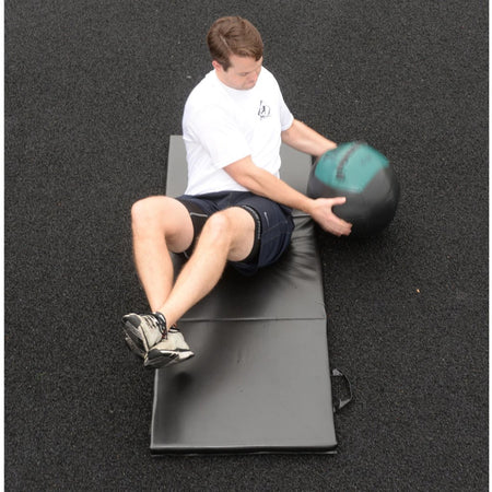 Athlete using 16lb soft medicine ball in Russian twist for core stability.