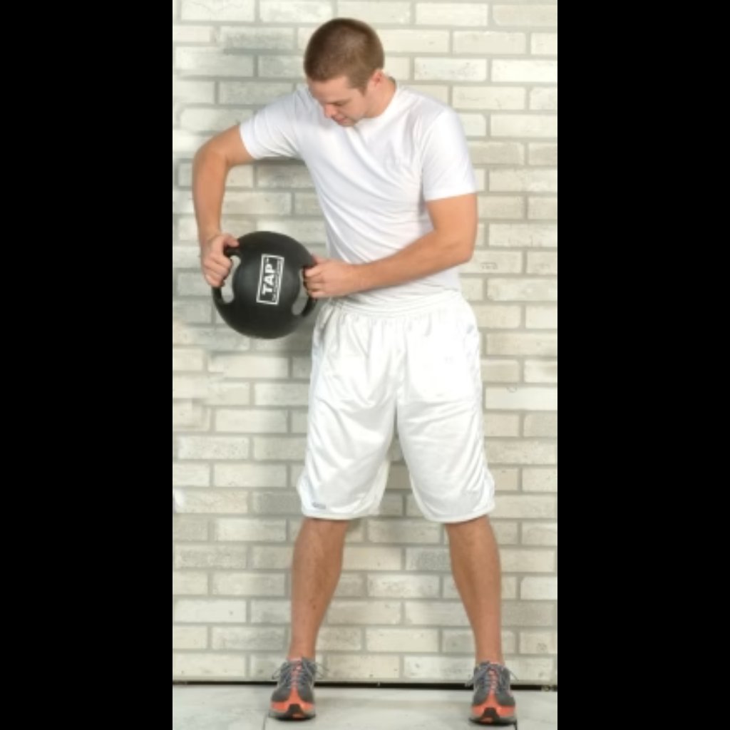 Double Handle Medicine Ball positioned beside an athlete’s hip—used for transitional movements targeting core stability and hip engagement during functional training.