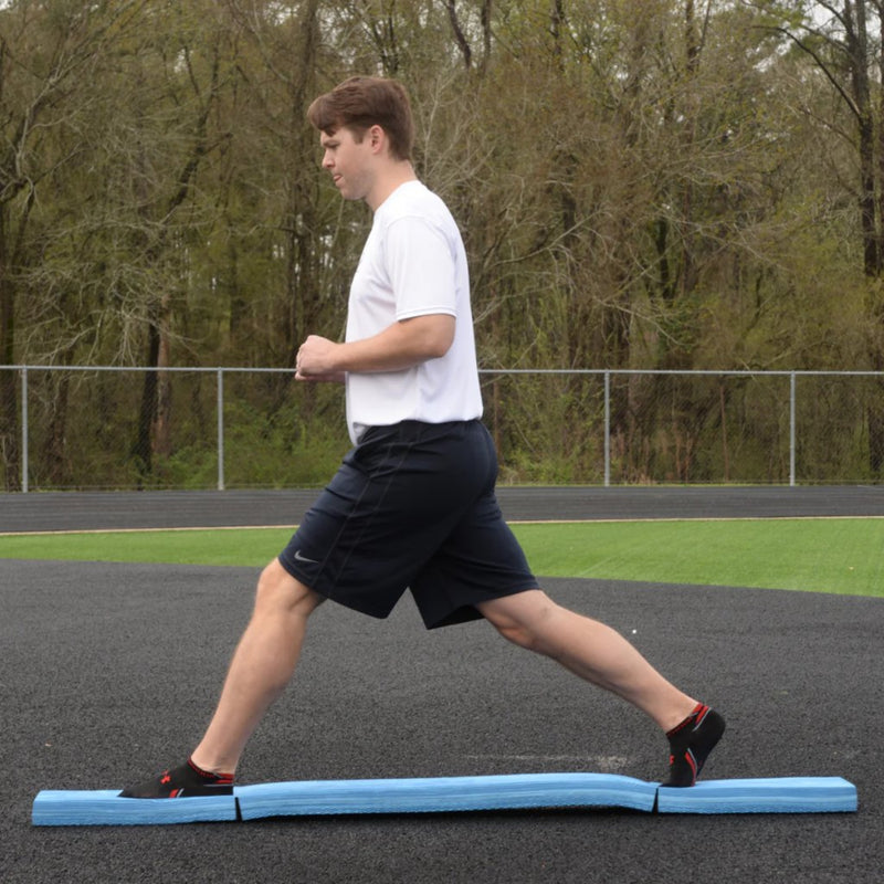 Athlete performing a standing split on the Folding Balance Beam, utilizing a narrowed unstable variable stimulus for lead-side stabilization and kinetic chain organization.
